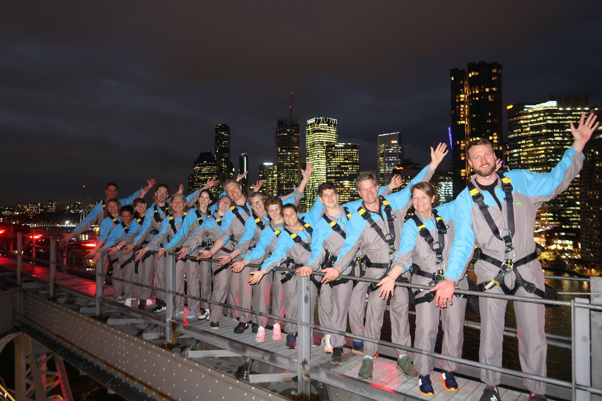 A group of people are standing on top of a bridge with their arms in the air.