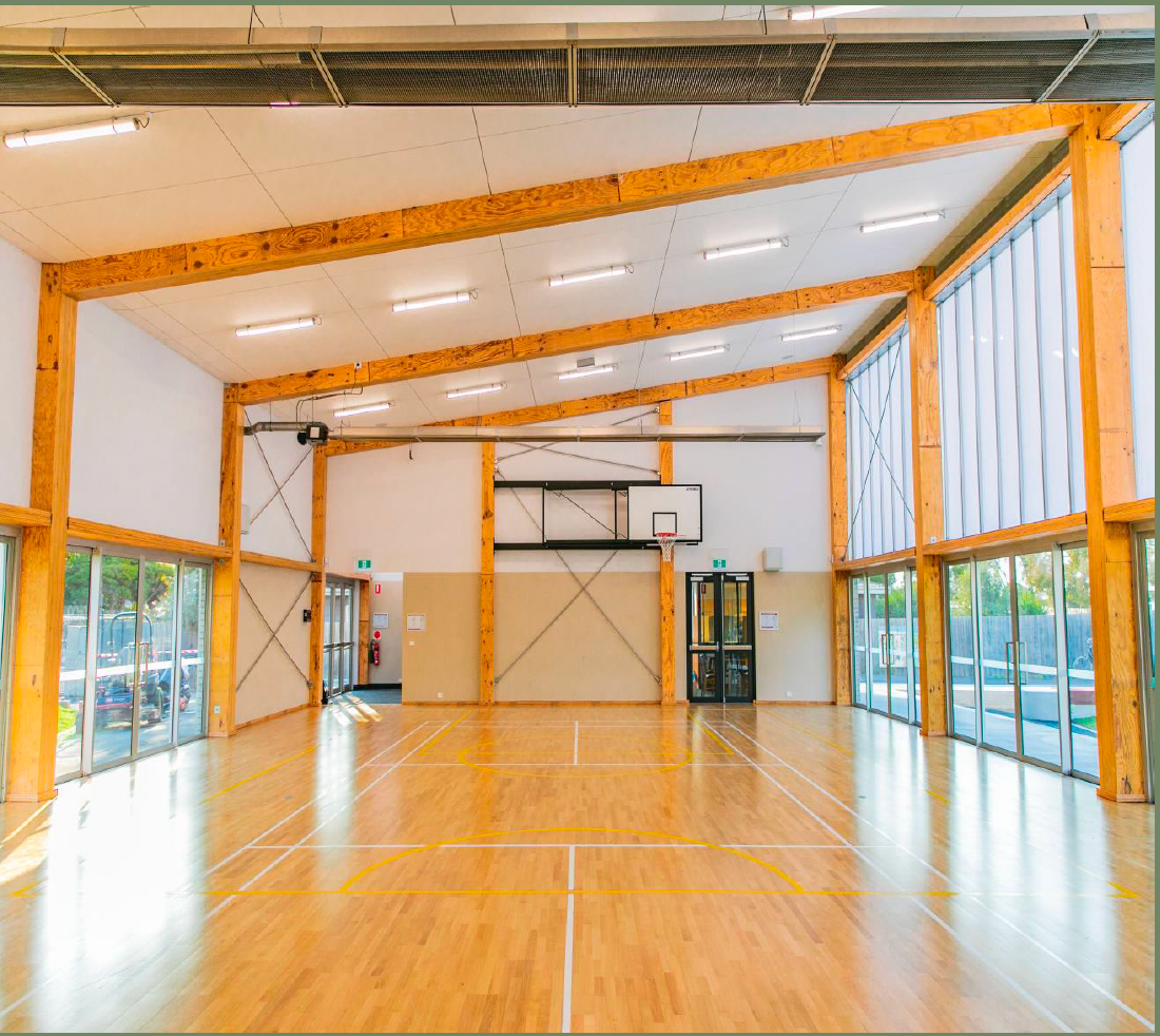 An empty gym with a wooden floor and lots of windows