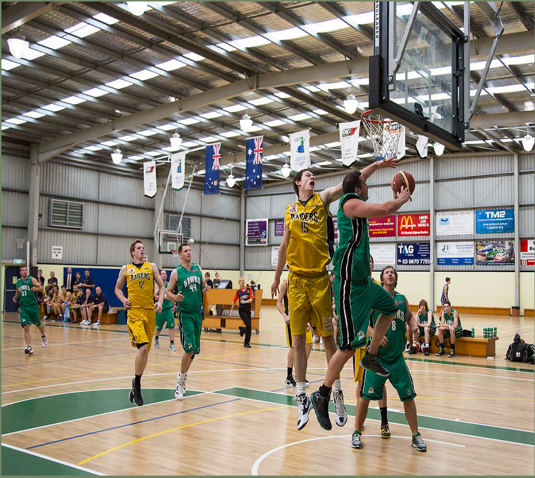 A group of men are playing a game of basketball in a gym