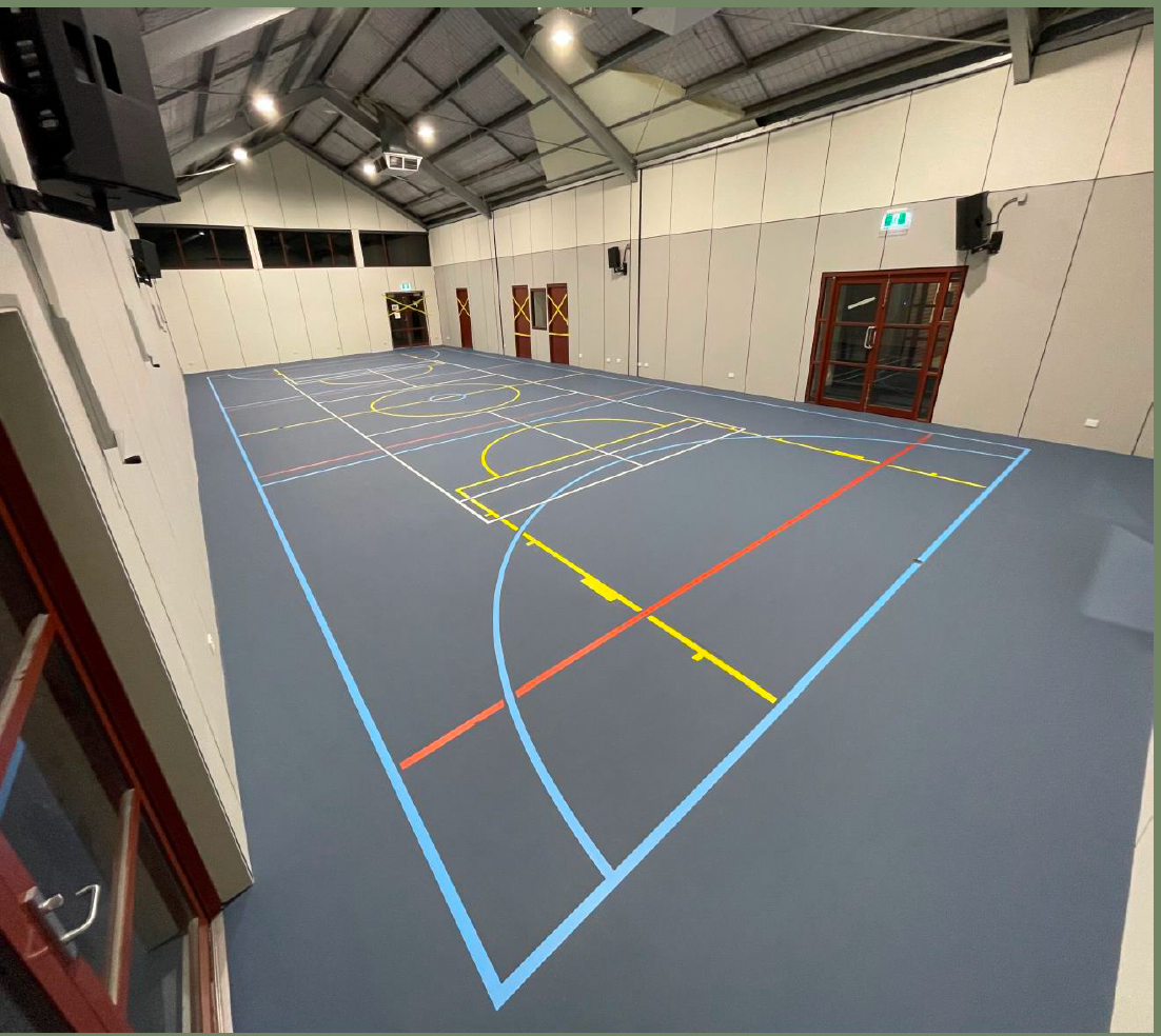 A large indoor basketball court with blue and yellow lines