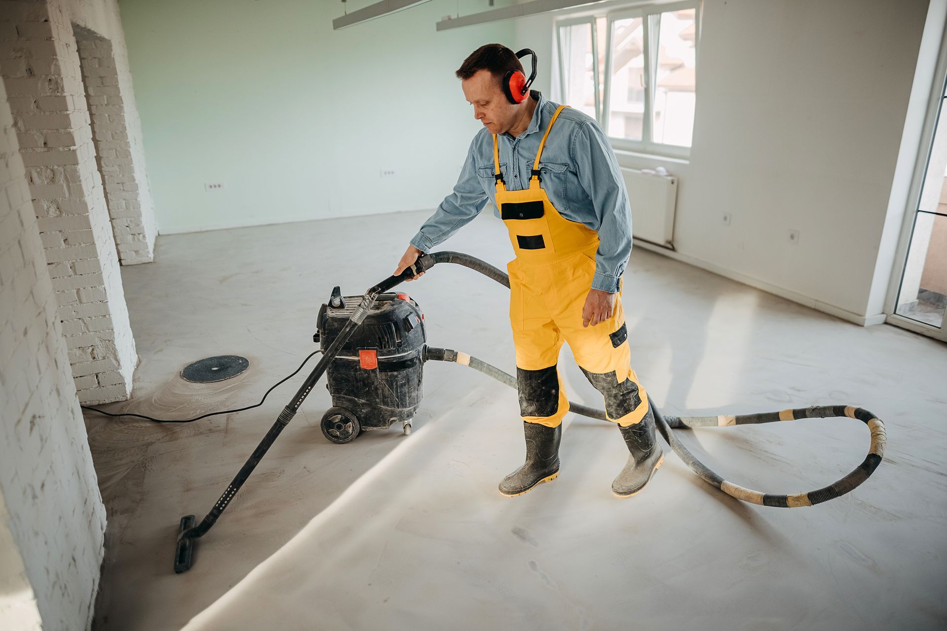 A man is using a vacuum cleaner to clean a floor.