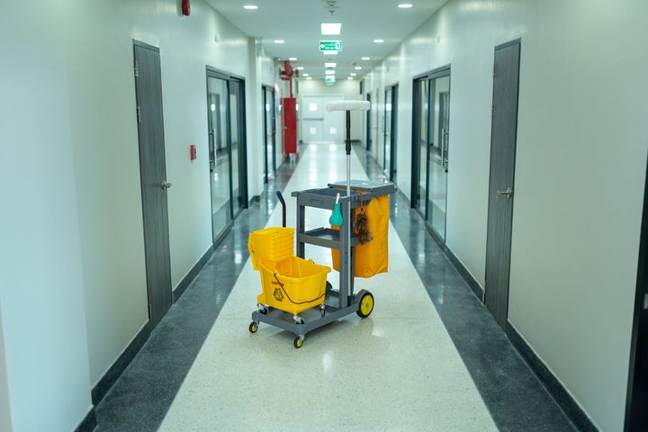 A cleaning cart is sitting in the middle of a hallway.