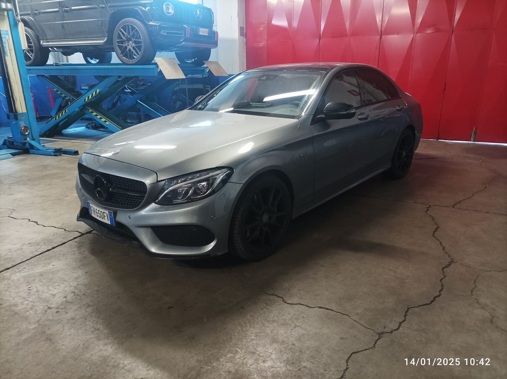 Un'auto argentata è parcheggiata davanti a un portone di garage rosso