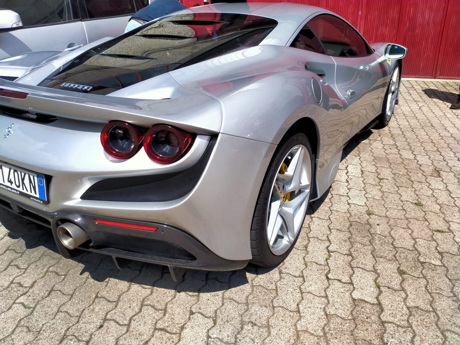 Un'auto sportiva argentata è parcheggiata su un vialetto di mattoni