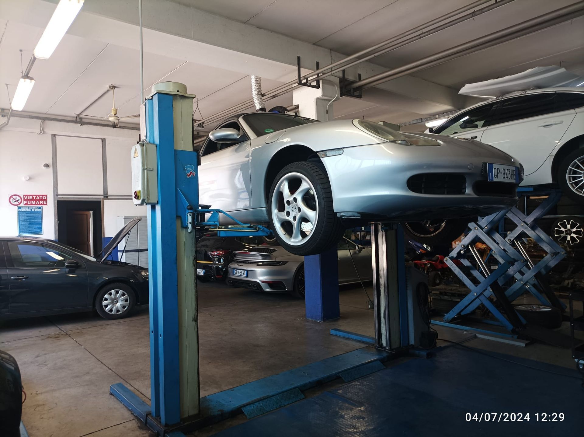 Un'auto sportiva argentata è su un ponte sollevatore in un garage