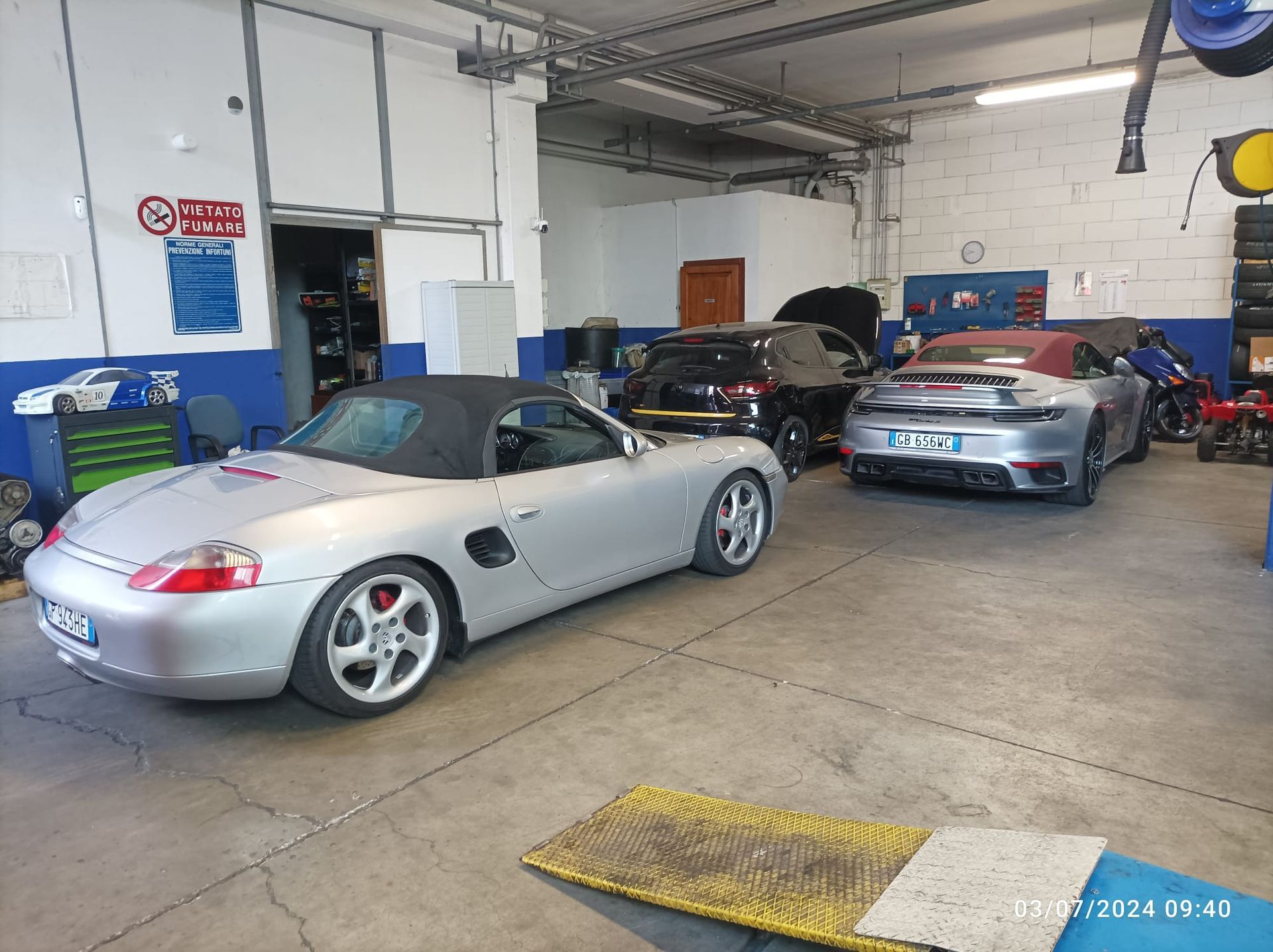 Un'auto sportiva argentata è parcheggiata in un garage con altre auto