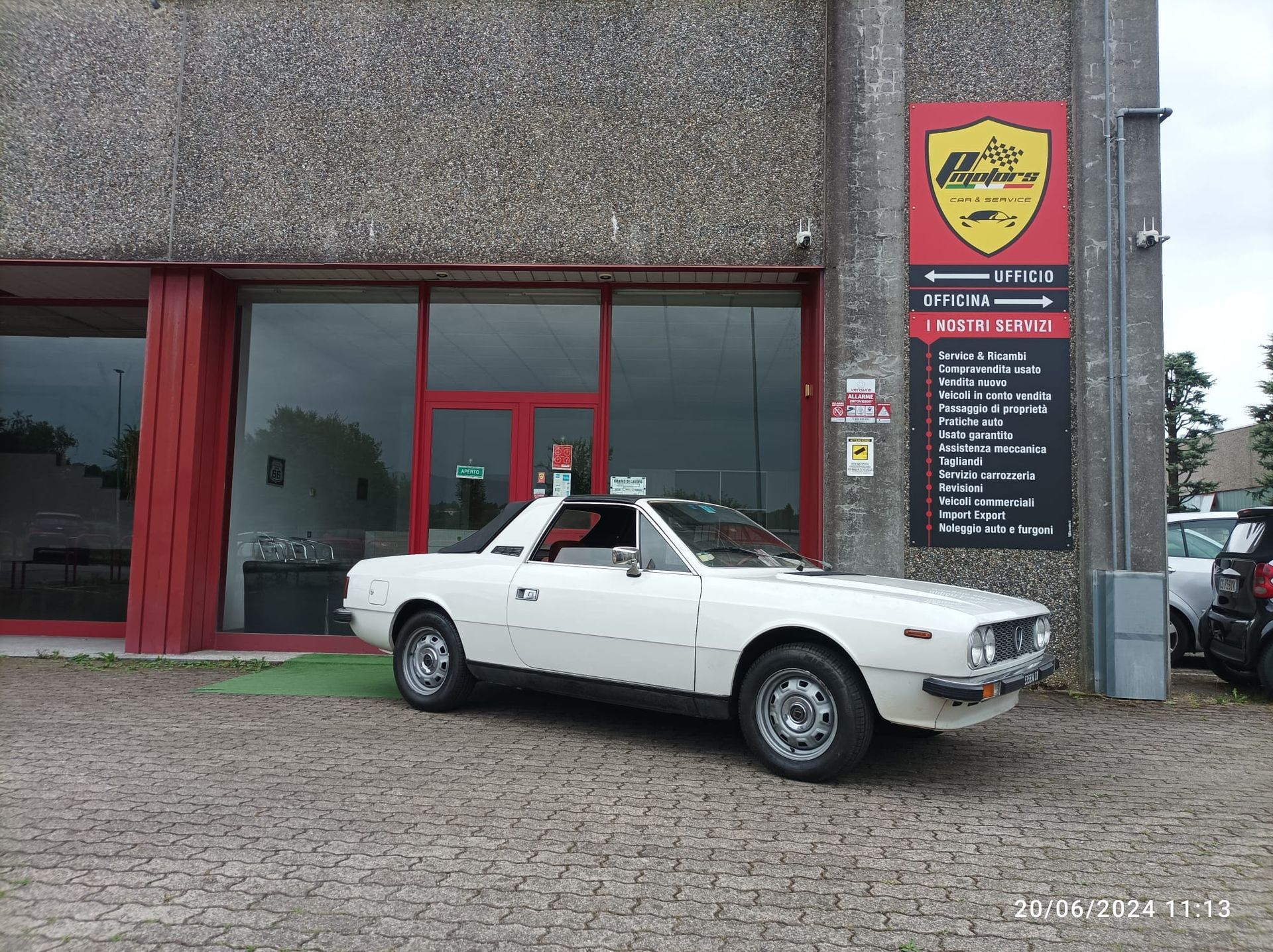 Un'auto bianca è parcheggiata davanti a una concessionaria di automobili