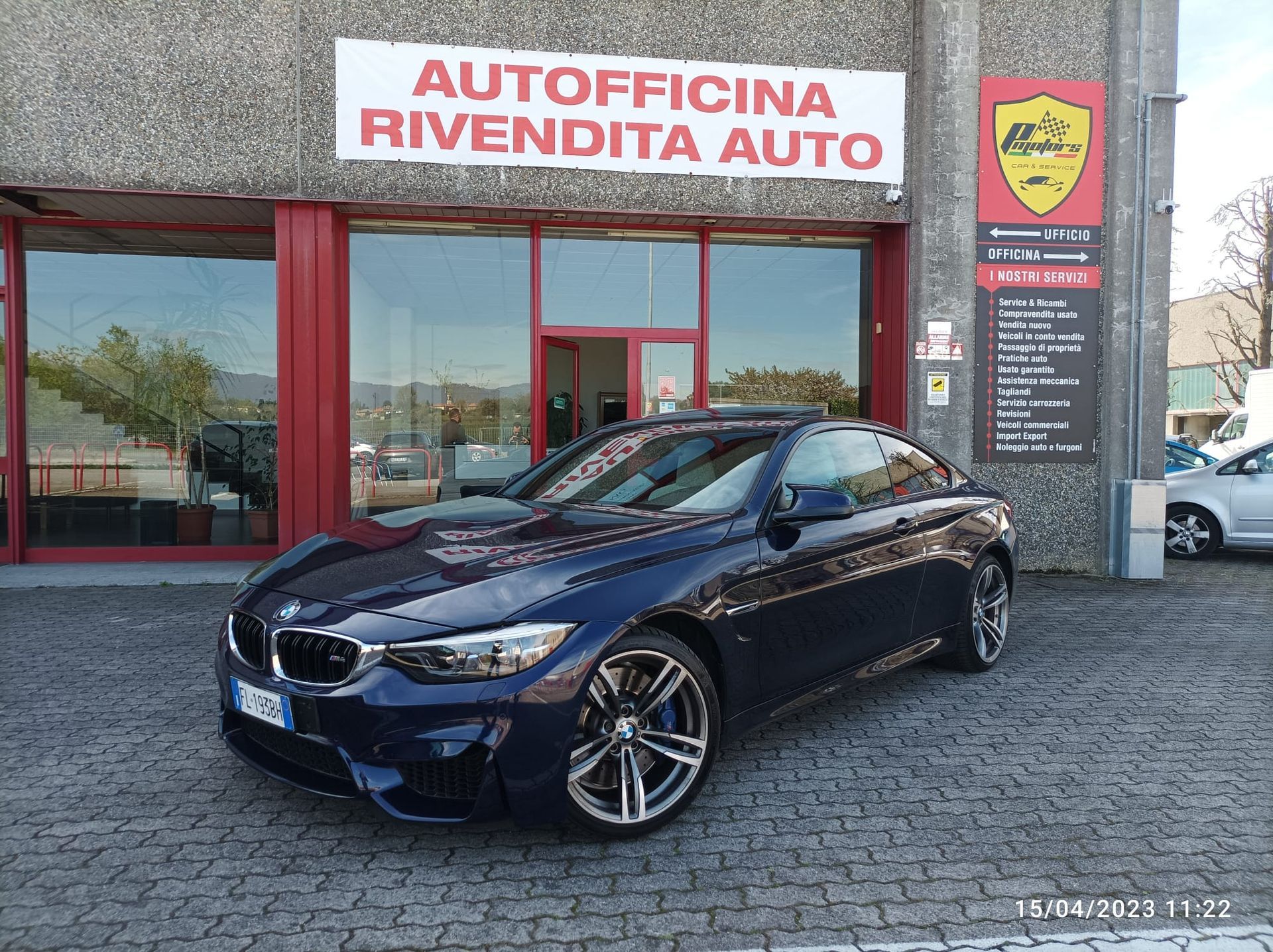 Un'auto blu è parcheggiata davanti ad un'autofficina rivendita auto