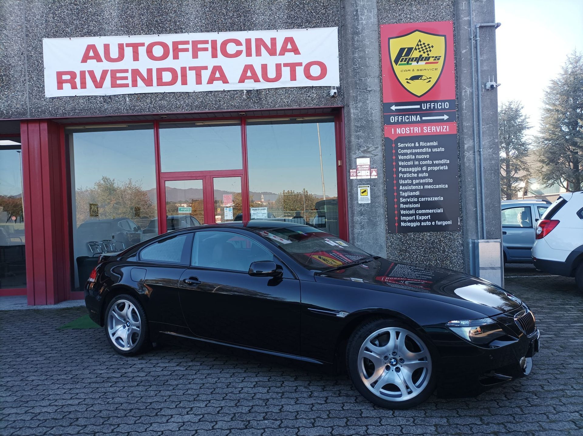 Un'auto nera è parcheggiata davanti a un'autofficina rivevendita auto