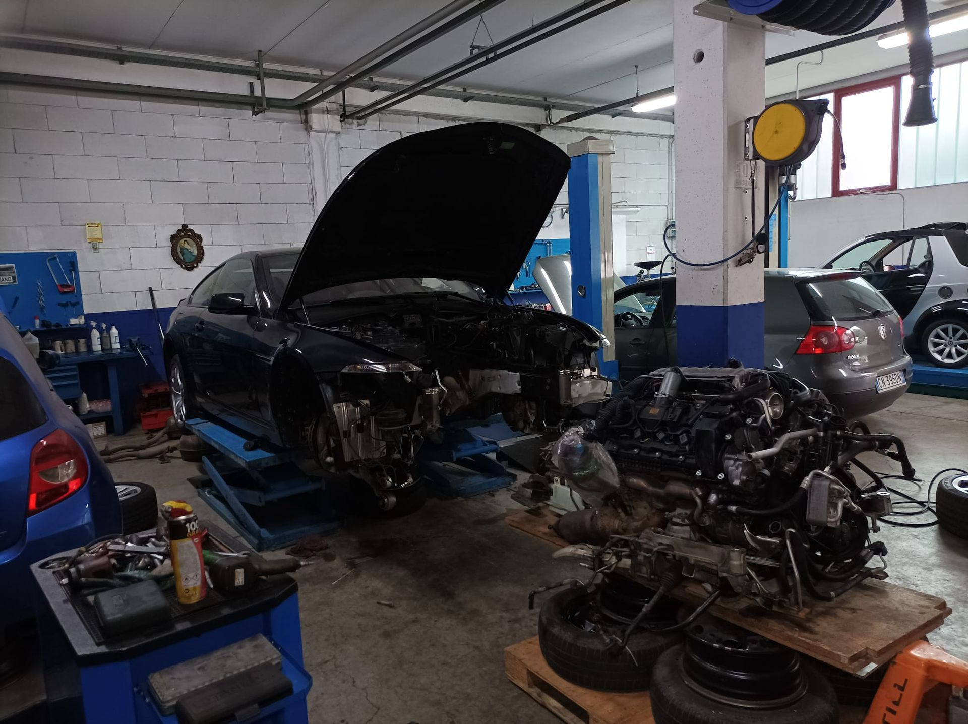 Un'auto con il cofano alzato viene riparata in un garage