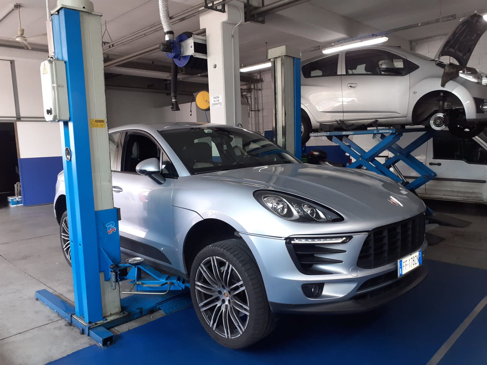 Una porsche argentata è su un ponte sollevatore in un garage