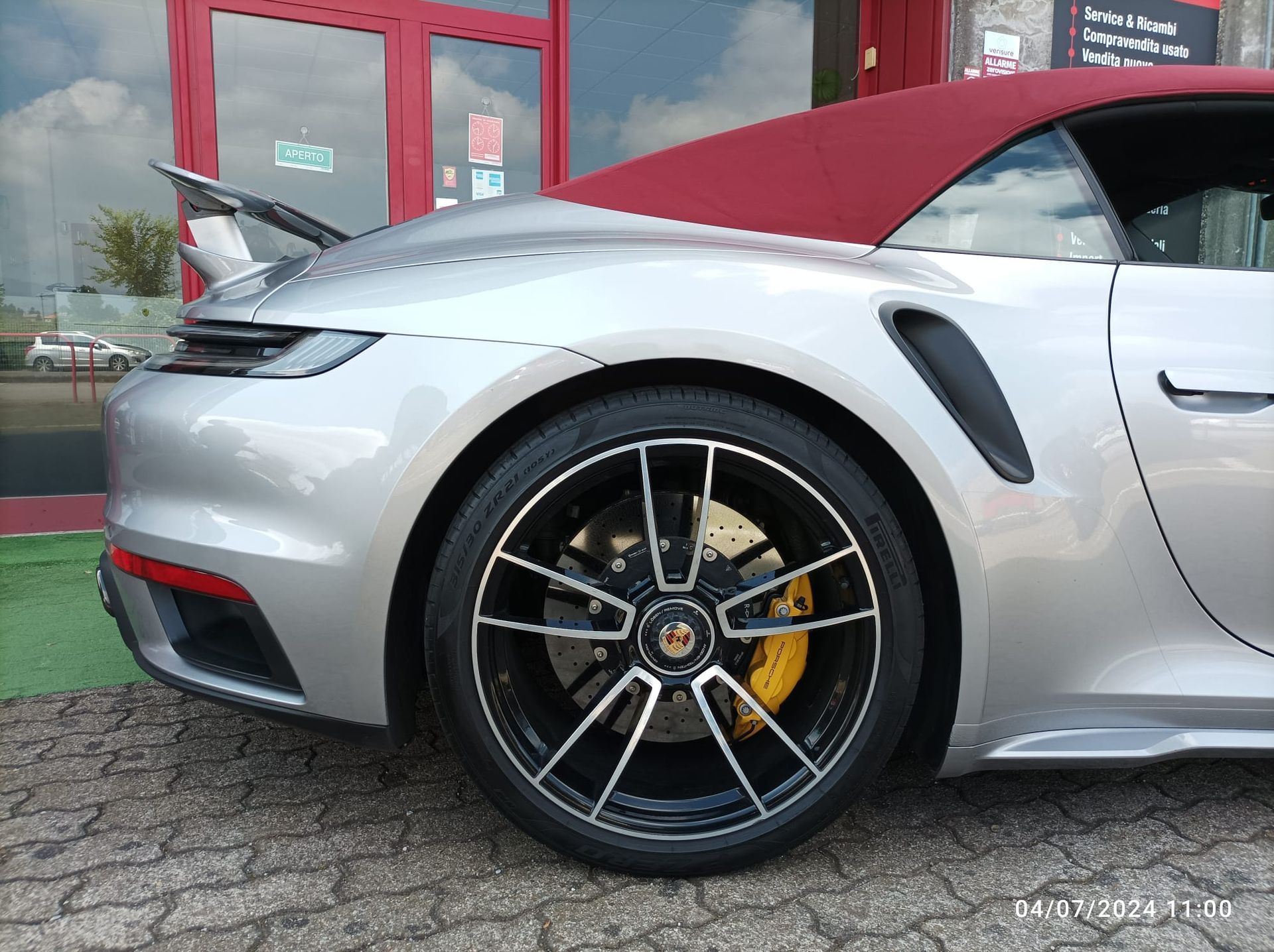 Un'auto sportiva argentata con il tetto rosso è parcheggiata davanti a un edificio