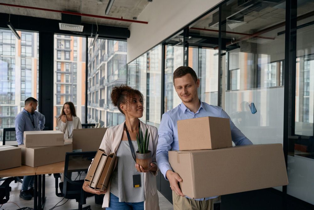 A Man And A Woman Are Carrying Boxes Into A New Office — Crichton Removals In North Geelong, VIC