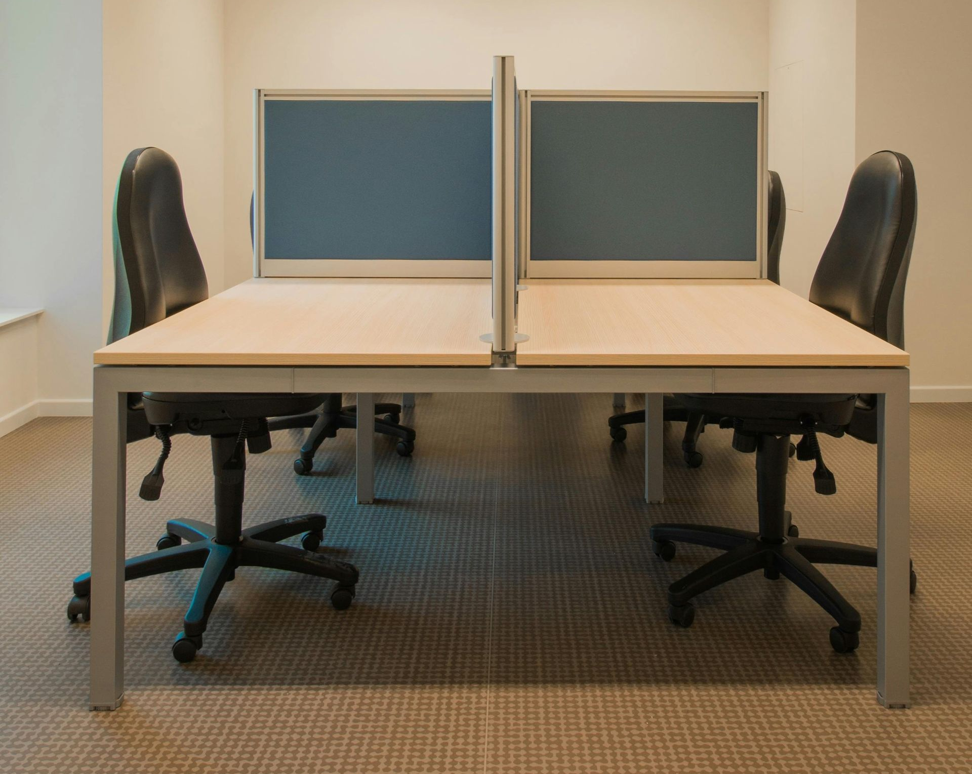 Office cubicle setup with four black office chairs and light blue dividers.