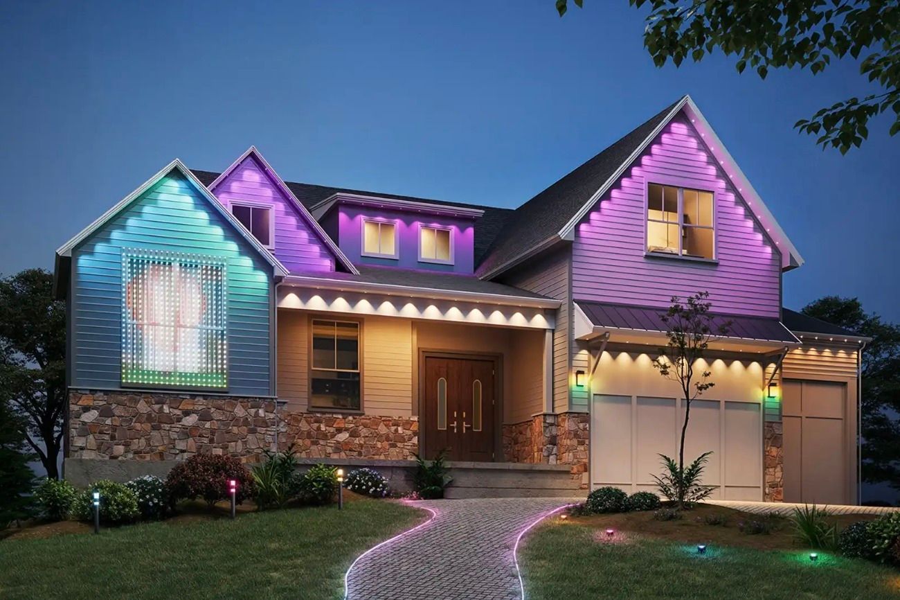 A suburban house at dusk with colorful LED accent lighting along the roofline and along a stone pathway.