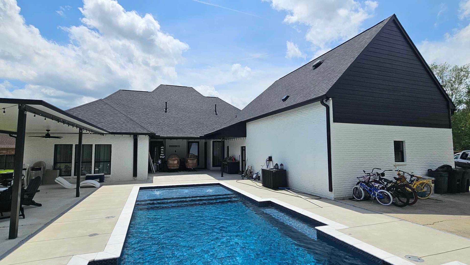 A large swimming pool is in the backyard of a house.