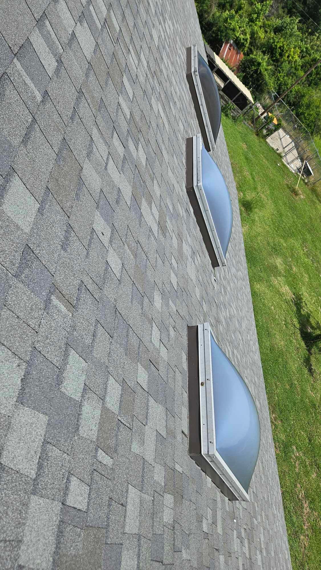 A close up of a roof with three skylights on it.