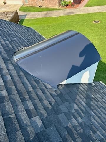 A roof with a skylight on it and a shadow of a person on it.