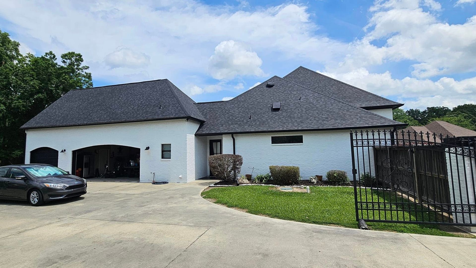 A white house with a black car parked in front of it.