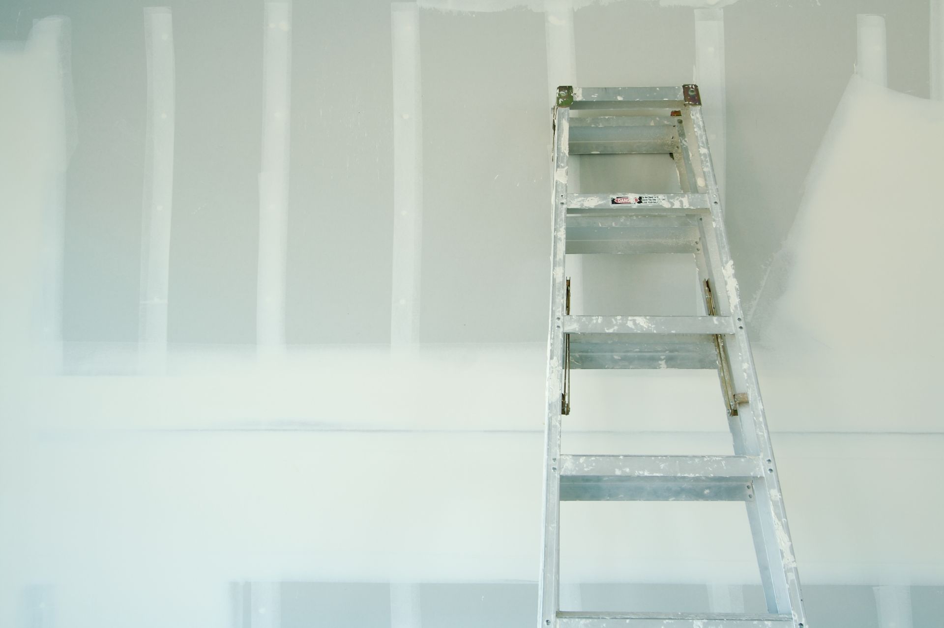 A ladder is leaning against a white wall.