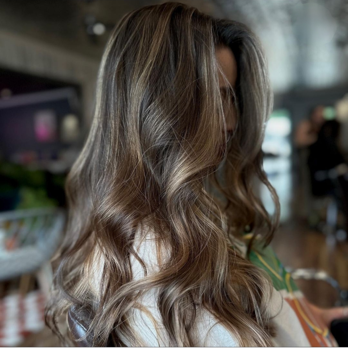 A woman with long brown hair is wearing a white shirt.