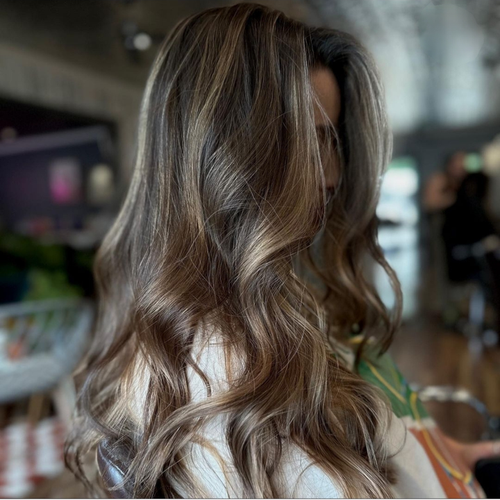 A woman with long brown hair is wearing a white shirt.