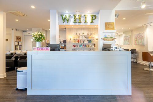 A white counter in a hair salon with a sign that says whip.