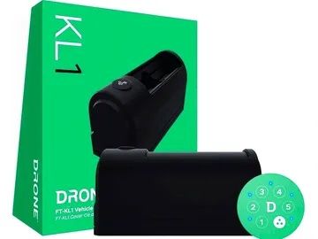 A black drone is sitting next to a green box.