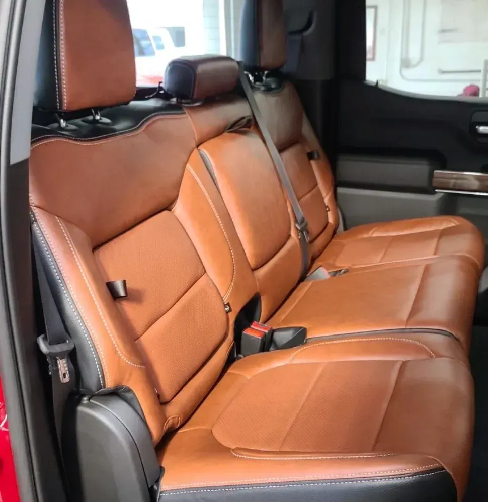 The back seat of a red truck with brown leather seats