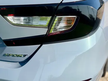 A close up of the back of a white car with a black tail light.