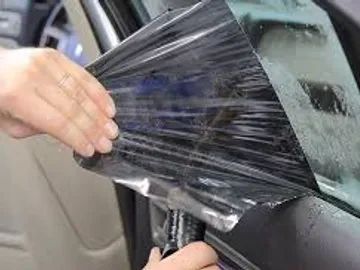 A person is applying window tinting to a car window.