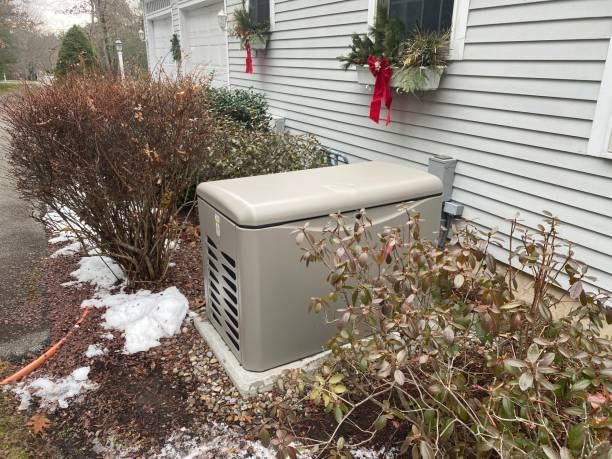 A generator is sitting on the side of a house next to a bush.