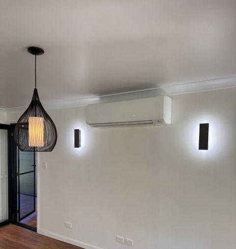 Window-mounted Air Conditioner Unit Installed on a Brick Building — Milton Electrical Projects In Kaban, QLD