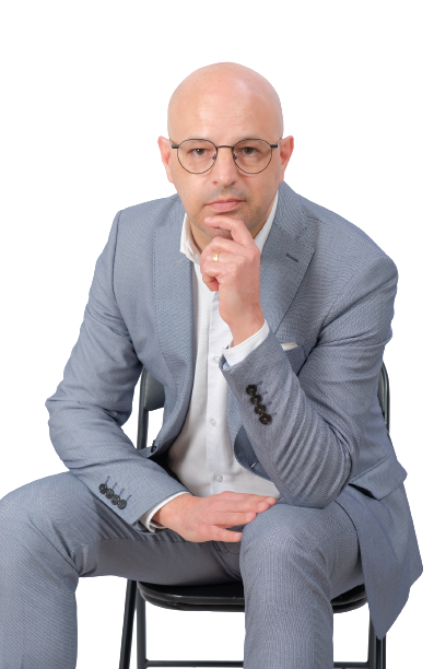A woman is sitting at a desk with a laptop and a vase of flowers.