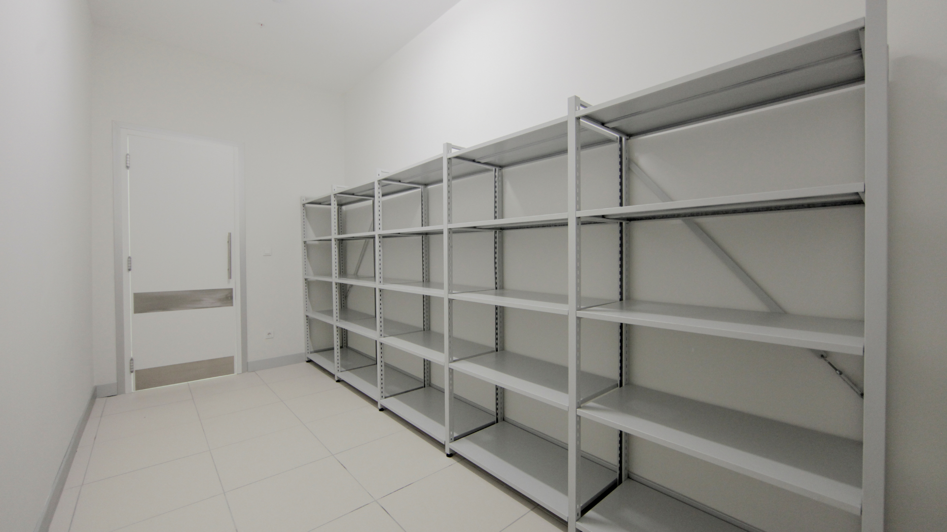 A room with a lot of shelves and a door.