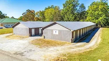 A row of garages are sitting next to each other in a grassy field.