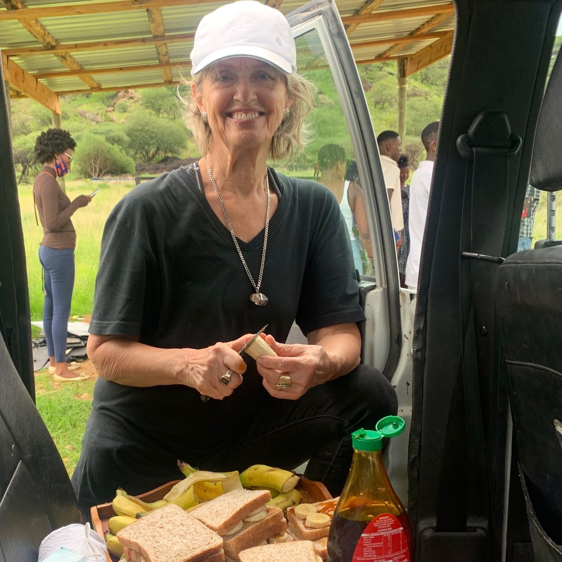 A woman is sitting in the back seat of a car holding a piece of bread.