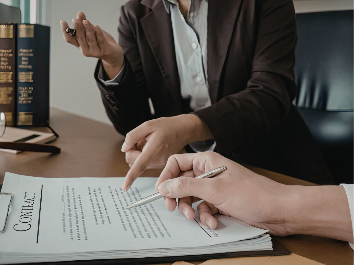 People at a table, reviewing documents. Papers, pens, and coffee cups are also present.