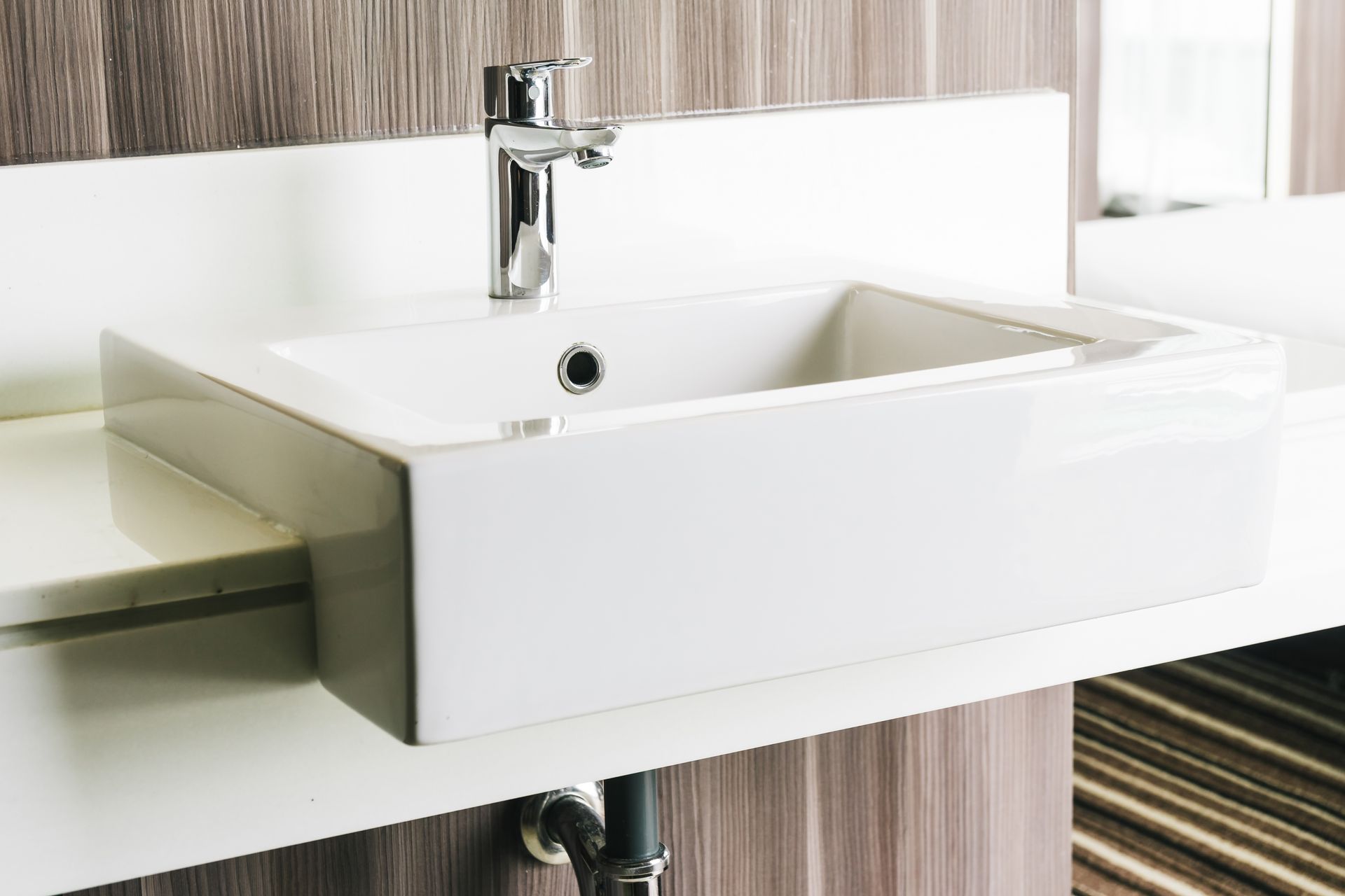 White rectangular bathroom sink with chrome faucet.