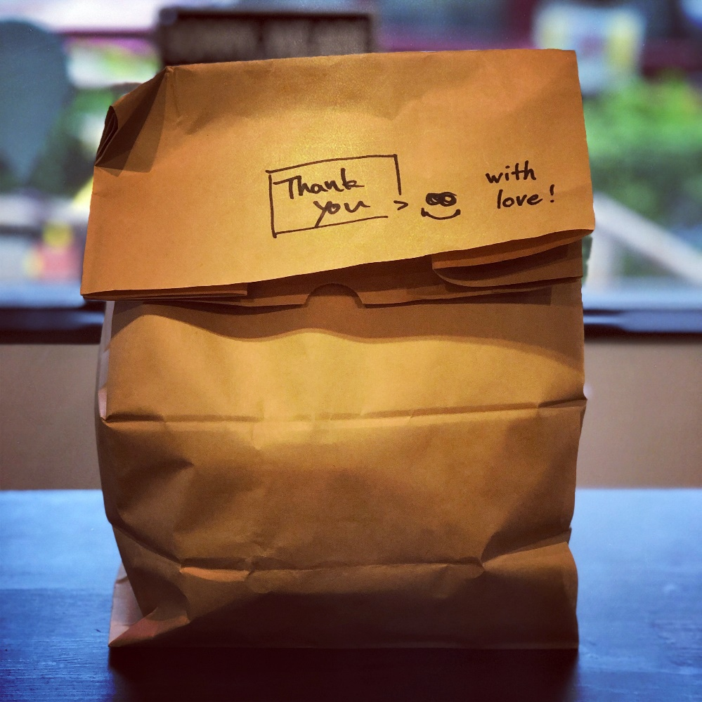 A paper bag with food, and words scribbled on it.