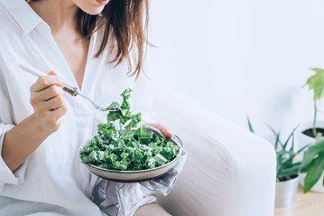 A woman eating a salad ordered from a restaurant online using a promo code