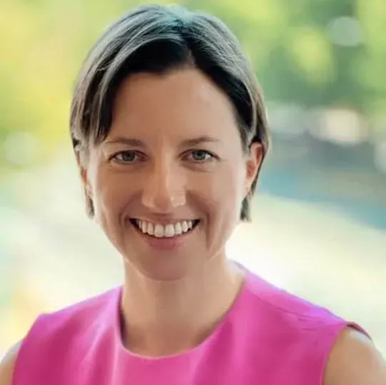 A woman in a pink dress is smiling for the camera.