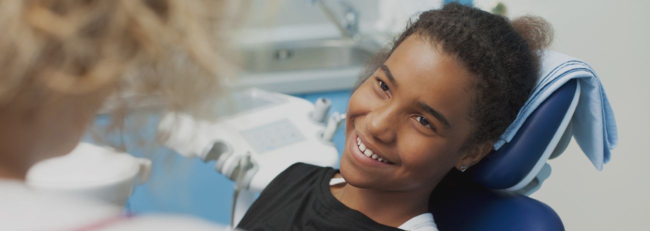A Young Boy is Sitting in a Dental Chair Smiling at the Dentist — Yeppoon Denture Clinic in Taranganba, QLD