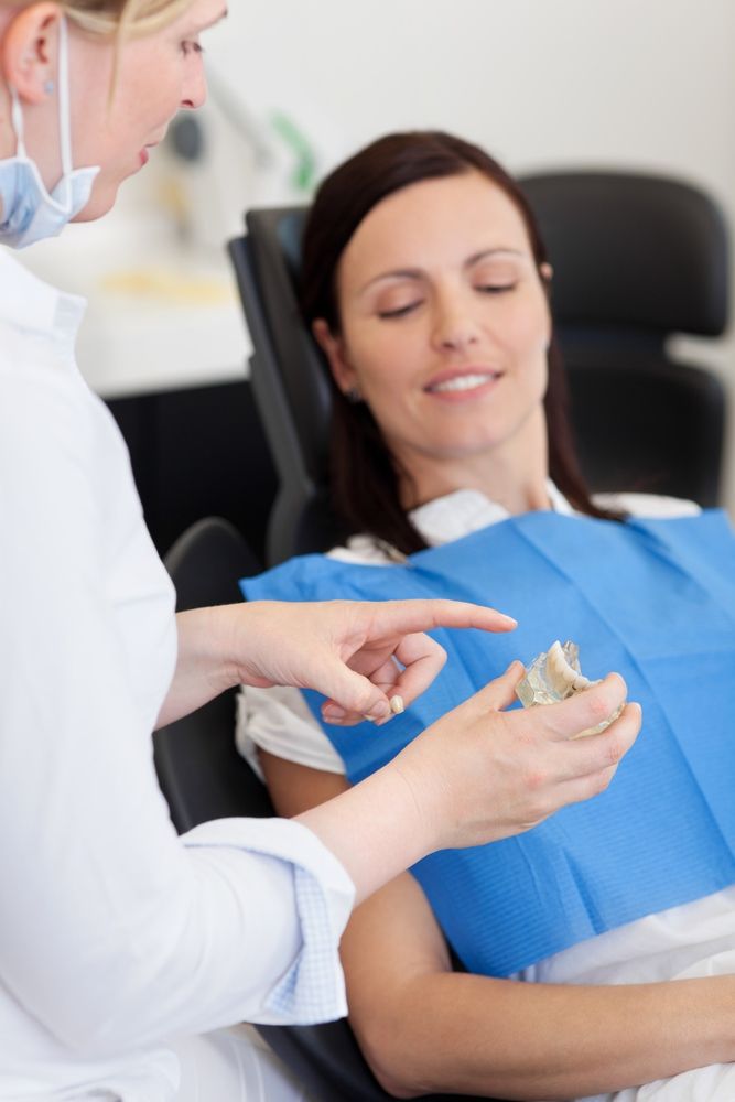A Woman is Sitting in a Dental Chair Talking to a Dentist — Yeppoon Denture Clinic in Taranganba, QLD
