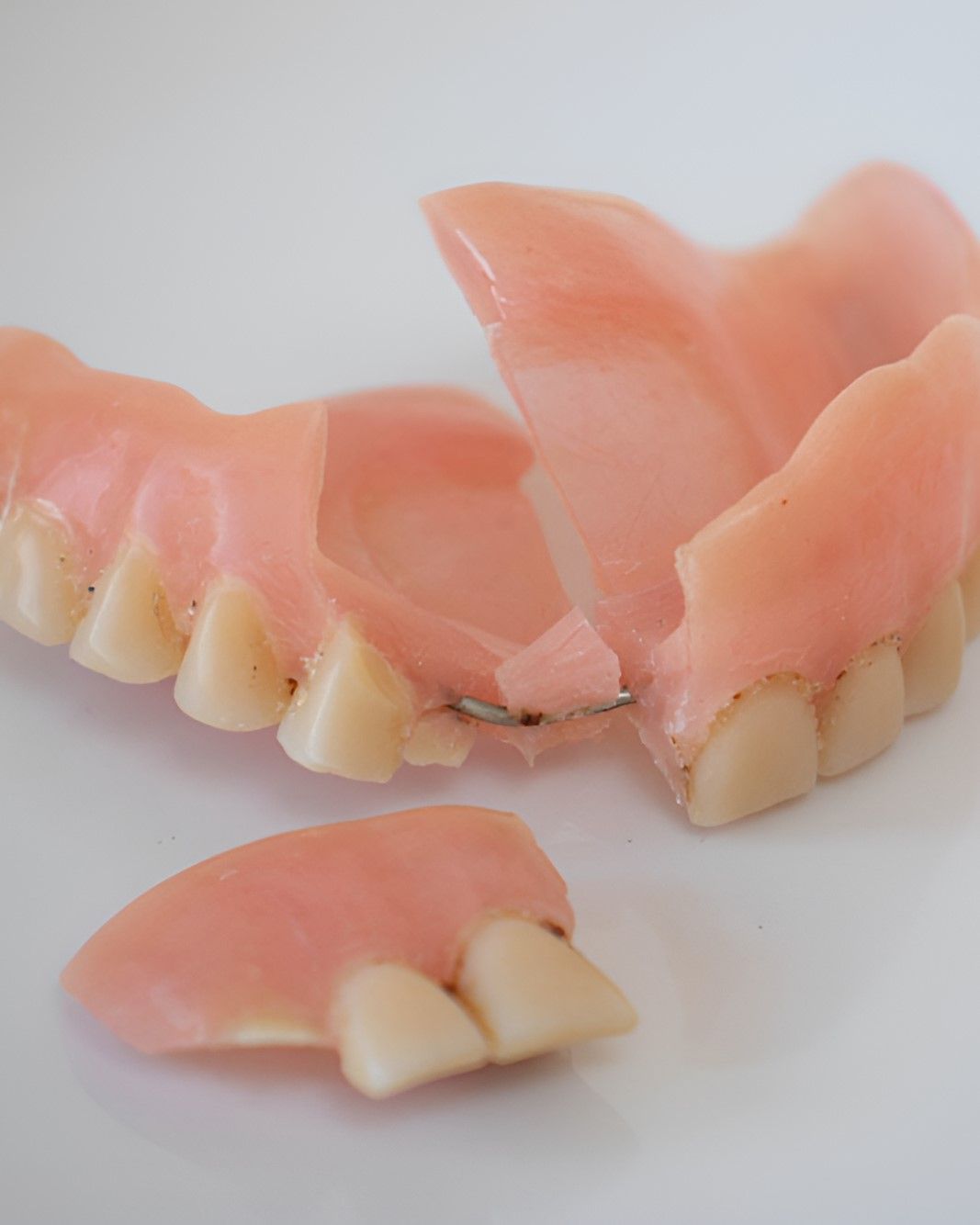A Close Up of a Broken Denture on a White Surface — Yeppoon Denture Clinic in Taranganba, QLD