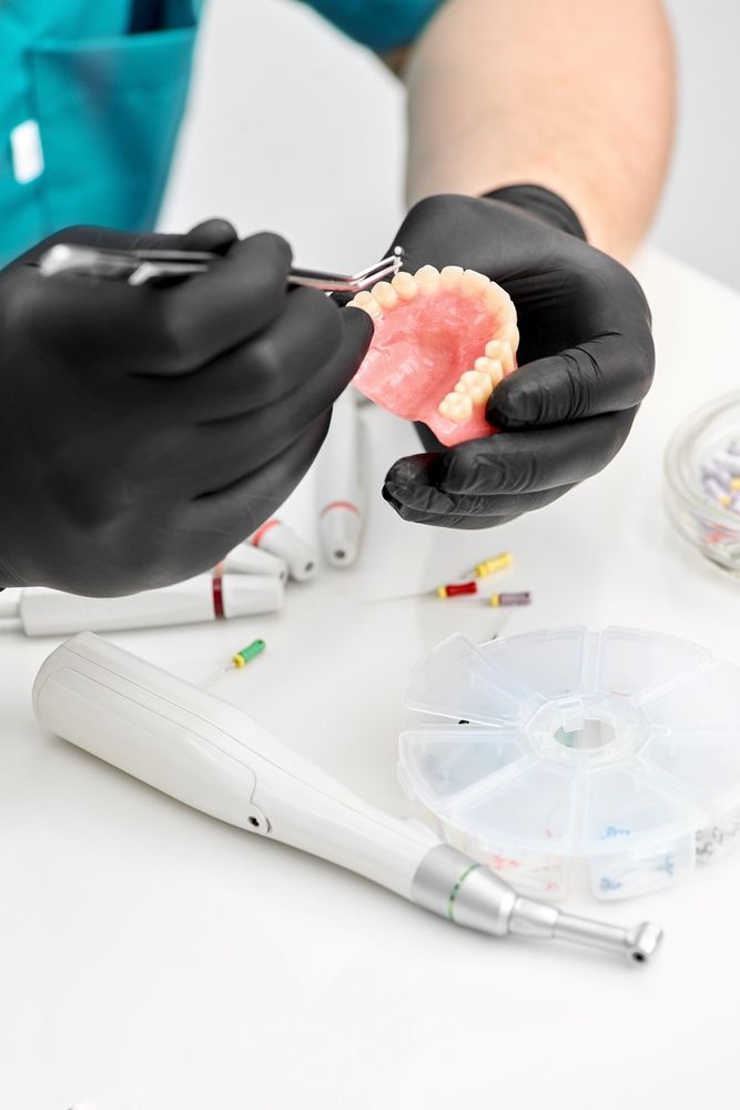 A Dentist is Working on a Denture With a Pair of Scissors — Yeppoon Denture Clinic in Taranganba, QLD