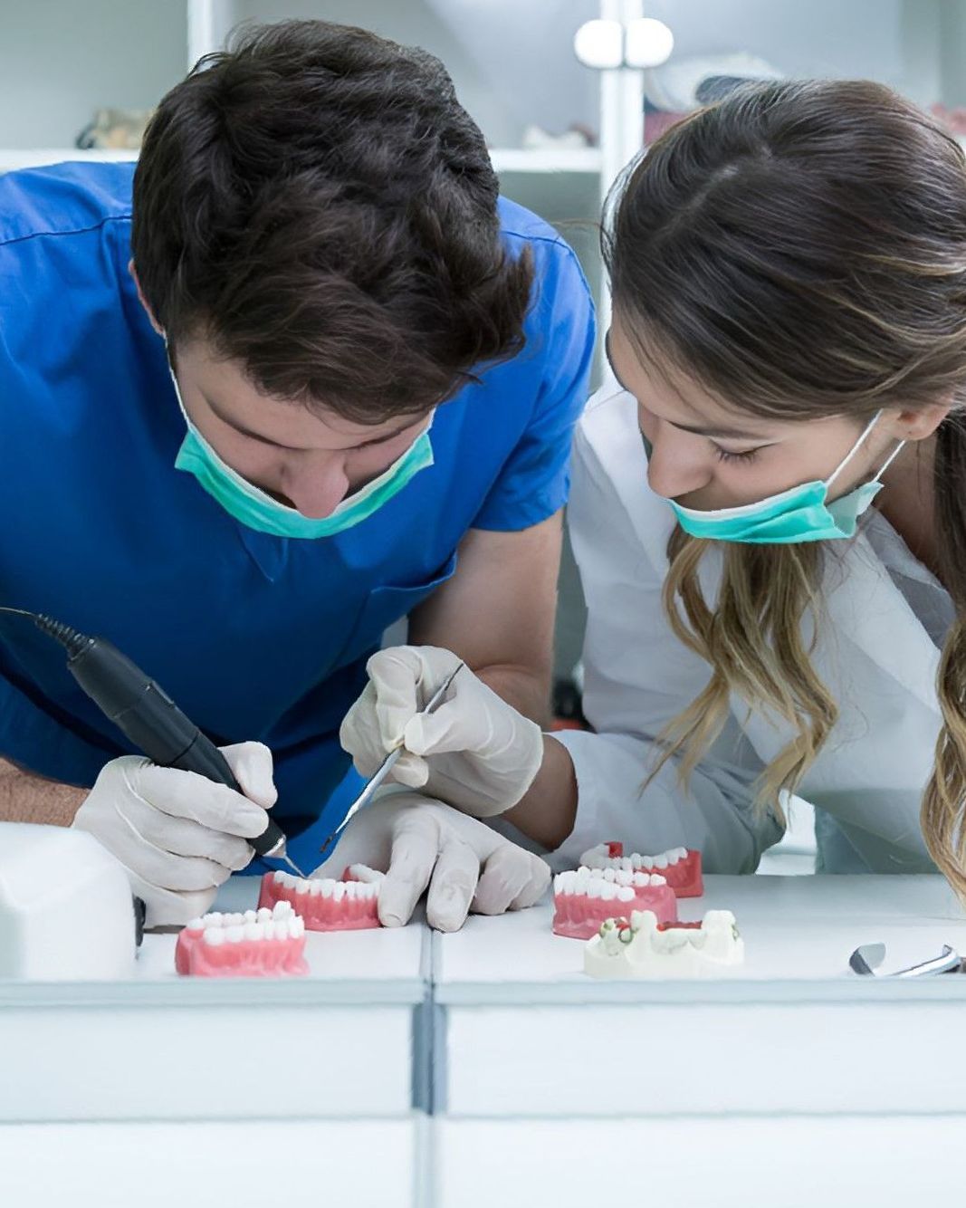 A Man and a Woman Are Working on a Model of Teeth — Yeppoon Denture Clinic in Gladstone, QLD