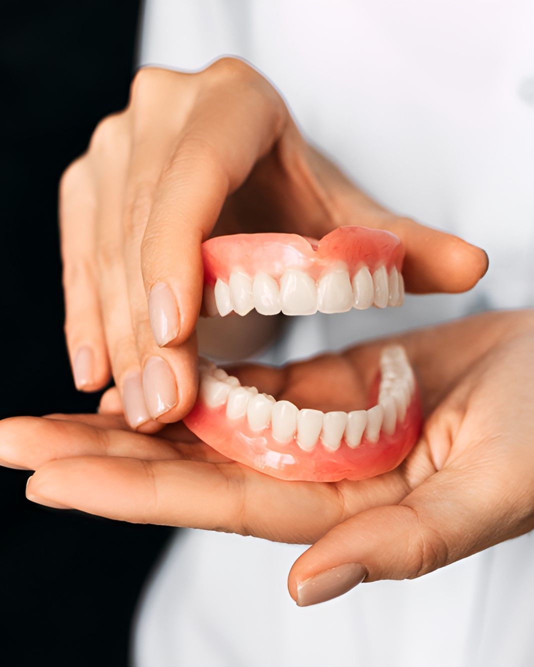 A Woman is Holding a Pair of Dentures in Her Hands — Yeppoon Denture Clinic in Taranganba, QLD