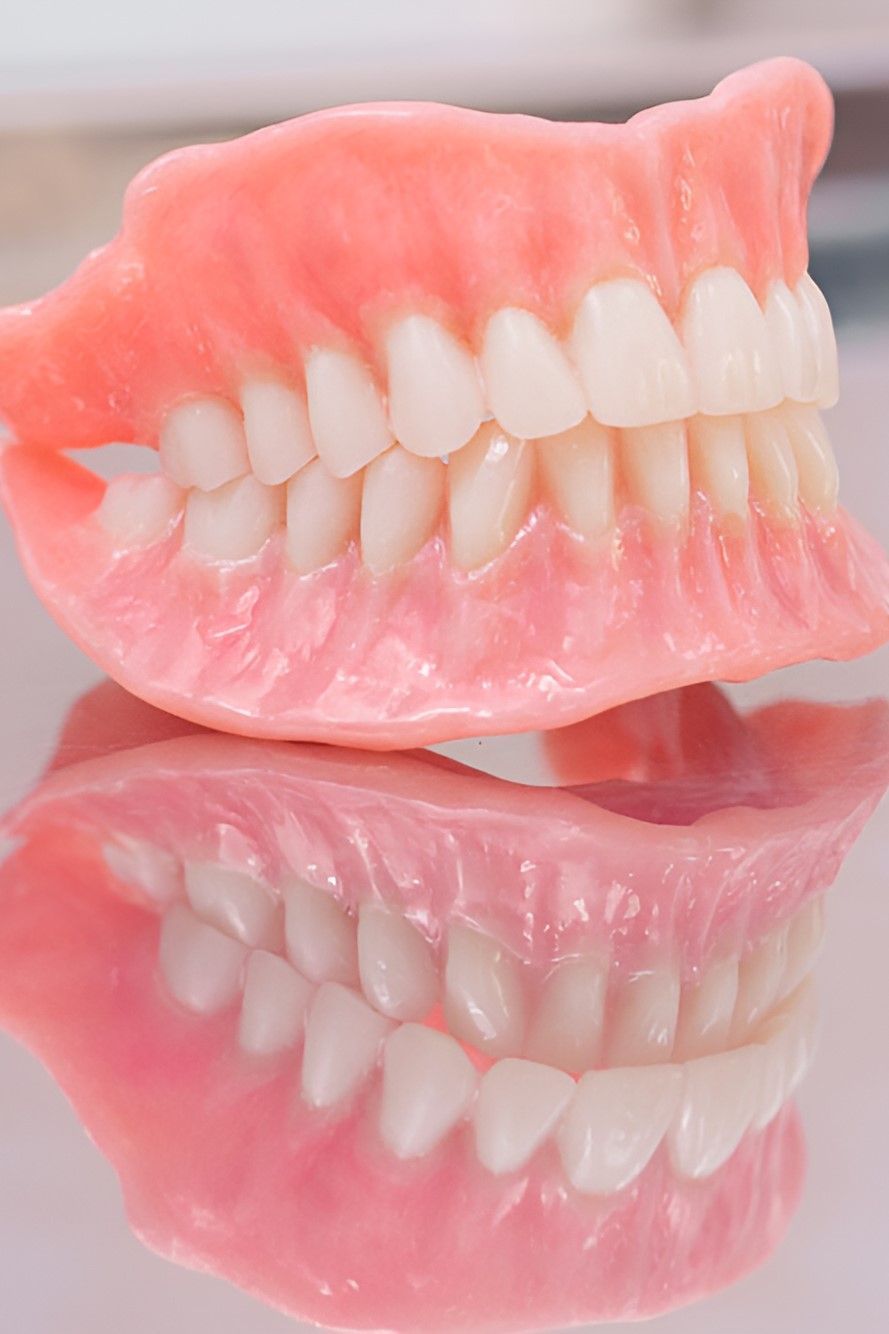 A Pair of Pink Dentures Sitting on Top of Each Other on a Table — Yeppoon Denture Clinic in Taranganba, QLD