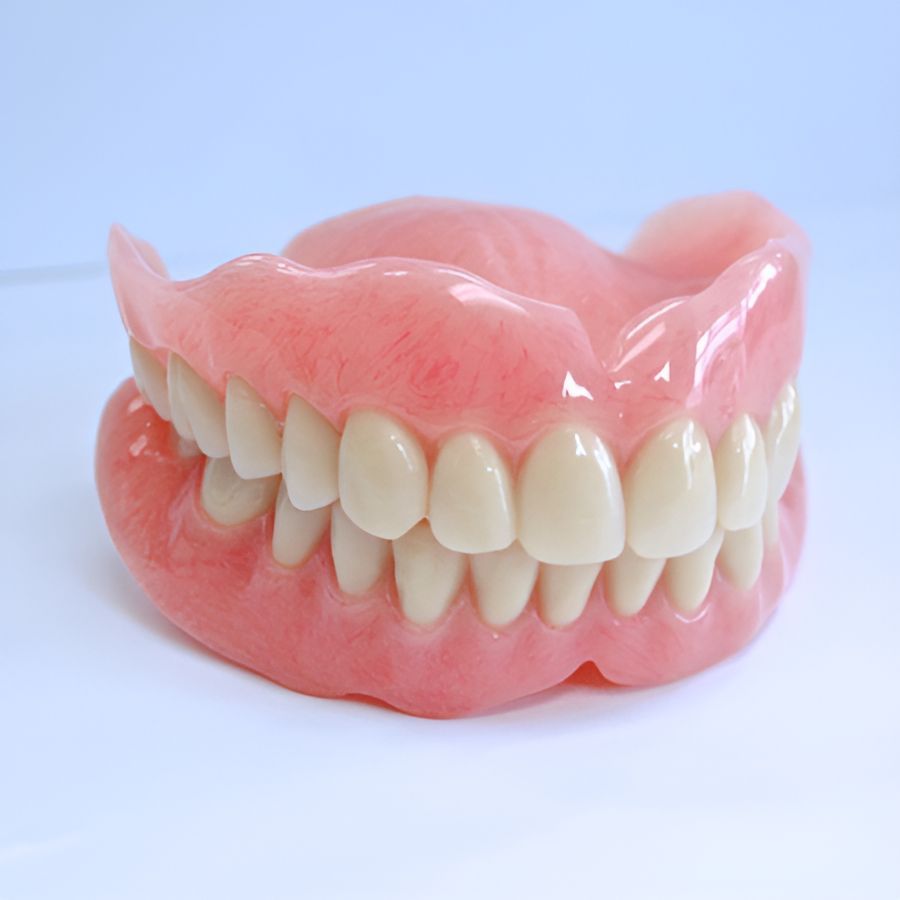 A Full Denture With White Teeth is Sitting on a White Surface — Yeppoon Denture Clinic in Taranganba, QLD